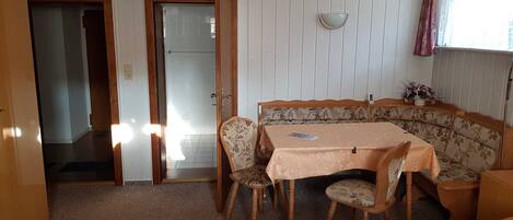 Una habitación con una mesa de comedor, sillas, un sofá, una cama y una ventana con cortinas.