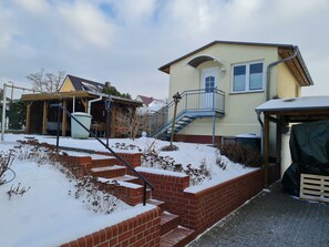 Ein zweigeschossiges Haus mit einer Ziegelstiege, die zu einem Balkon führt, einer Veranda und einer Garage.