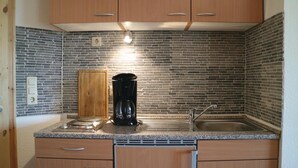 A kitchen with wooden cabinets, a granite countertop, a coffee maker, and a stainless steel sink. - Cozy apartment in Thulendorf/Sagerheide (Thulendorf/Sagerheide)