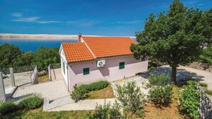 Una casa de planta baixa amb teulada de rajola vermella, un garatge petit adossat i un vial pavimentat.