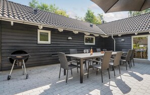 An outdoor patio with a grill, dining table, and chairs. - Nice home in Væggerløse with sauna (Væggerløse)