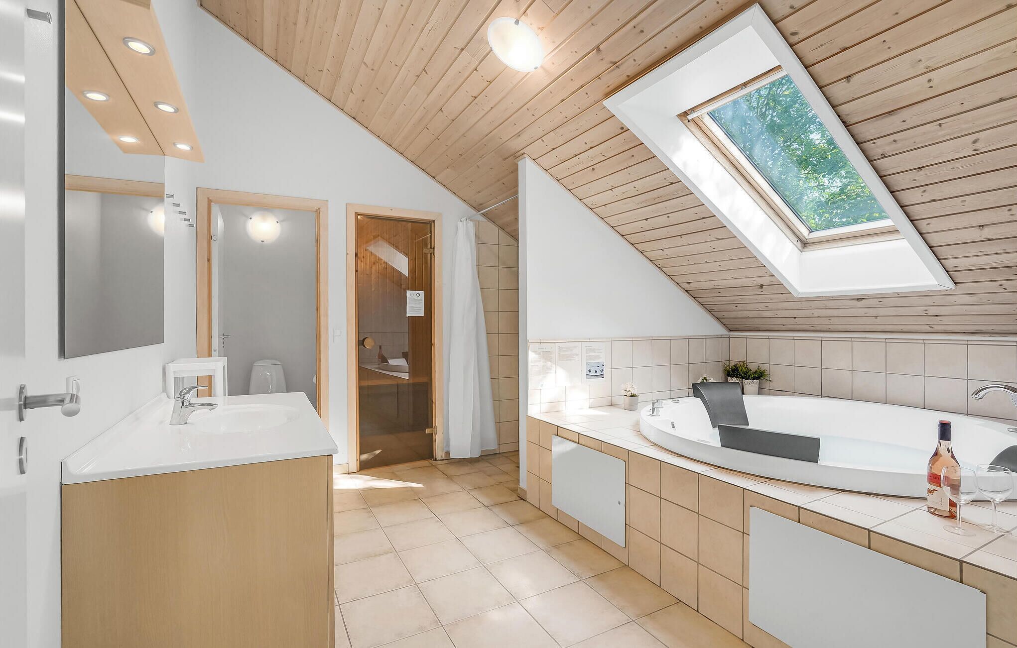 Een moderne badkamer met dakraam, een groot bad en een aparte douche.