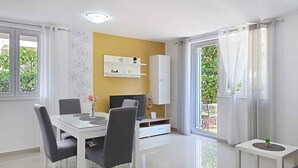 Un comedor moderno con una mesa blanca, sillas grises y un televisor.