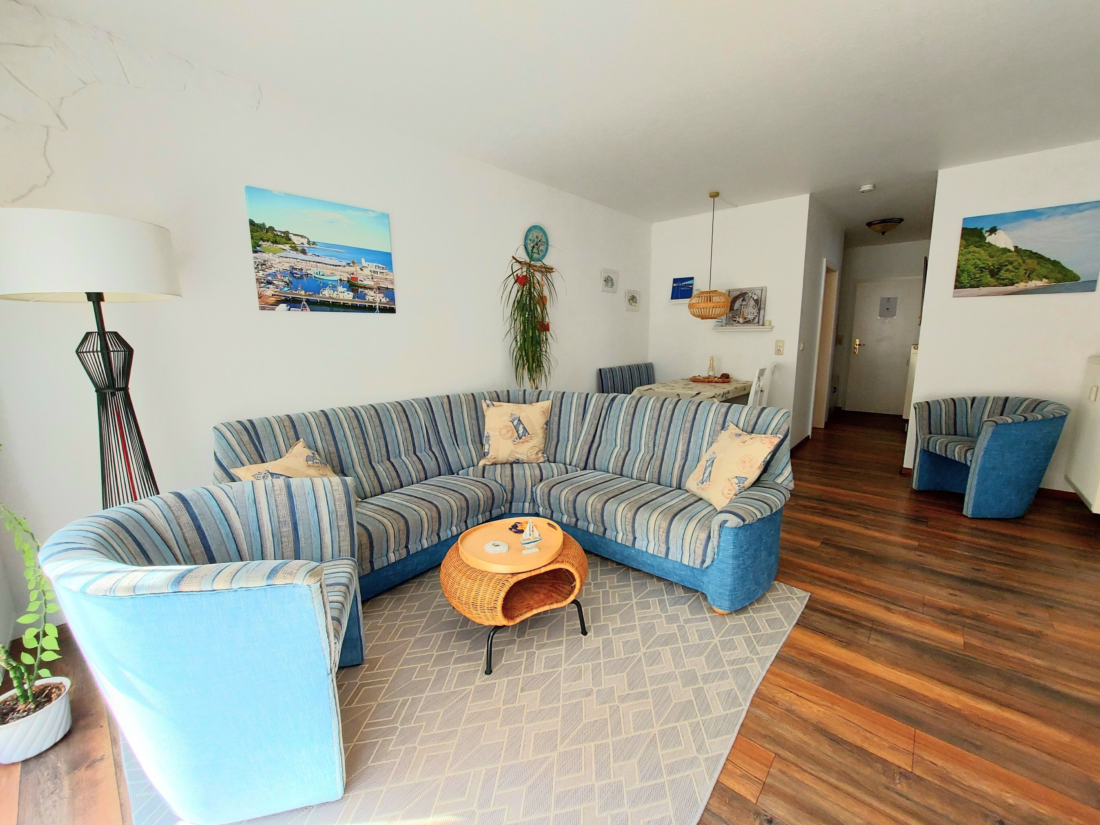 A living room with a blue-striped sofa, a small round table, and a potted plant.