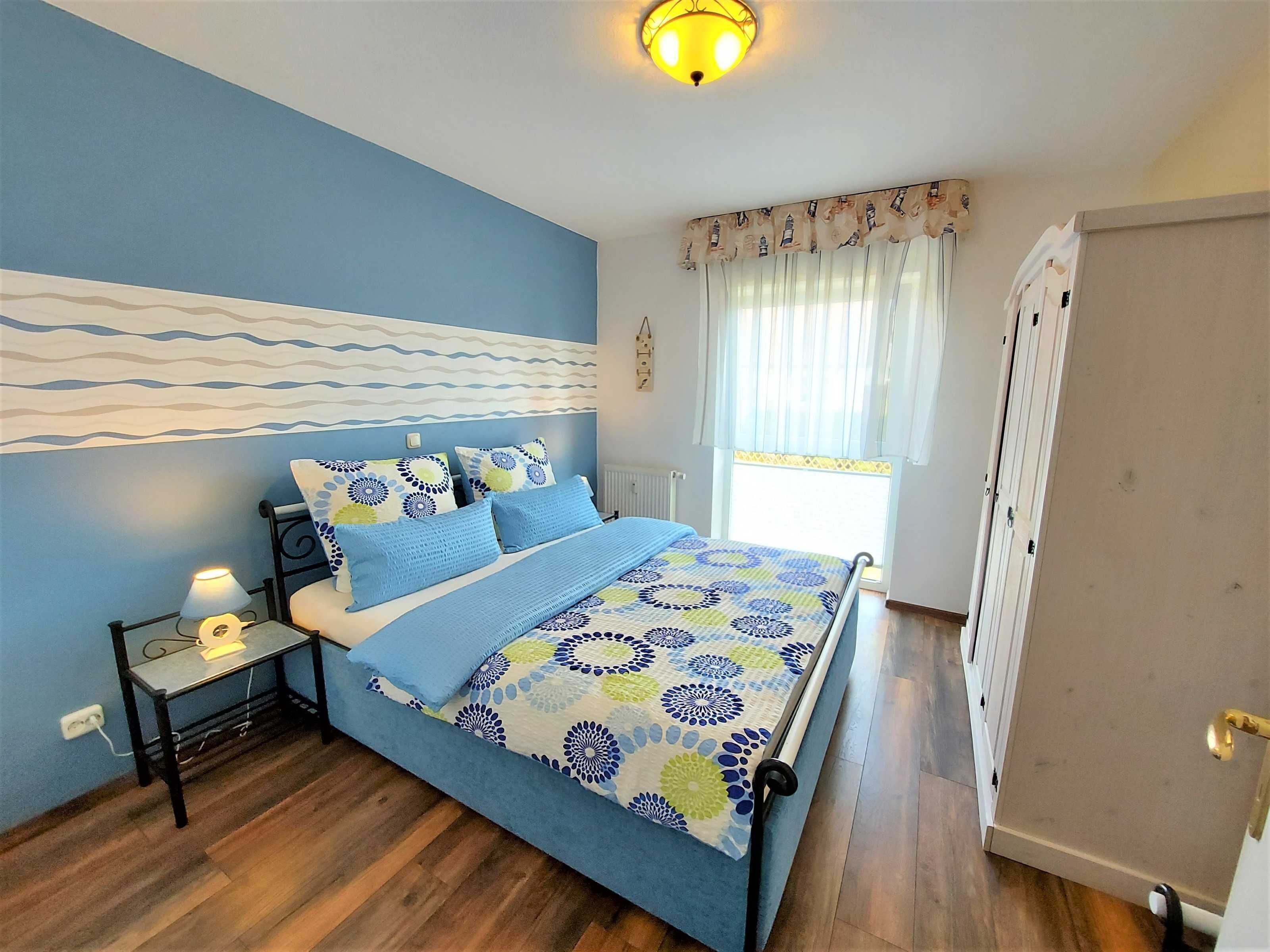 A bedroom with a bed, bedside table, lamp, and a window with curtains.