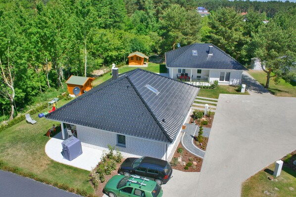 A residential property with a large house, a smaller cabin, and a driveway with two cars.