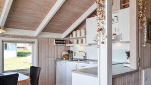 A kitchen with wooden cabinets, a sink, and a countertop. There is a window with a view of greenery outside. - 2 bedroom nice home in Hvide Sande (Hvide Sande)