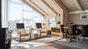 A cozy room with wooden beams, a dining area, and a large window with blinds. - 2 bedroom nice home in Hvide Sande (Hvide Sande)