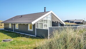 A single-story house with a sloped roof, large windows, and a chimney. - 2 bedroom nice home in Hvide Sande (Hvide Sande)