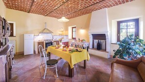 A dining area with a brick ceiling, a kitchen with a gas stove, and a fireplace. - Beautiful home in Aramengo (AT) (Aramengo (AT))