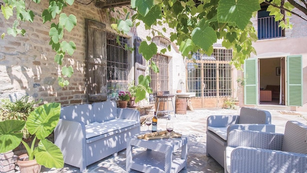 A patio with wicker furniture, a table with wine glasses, and potted plants. - Beautiful home in Aramengo (AT) (Aramengo (AT))
