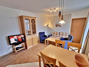 A living room with a television, a wooden cabinet, a sofa, a coffee table, and a floor lamp.