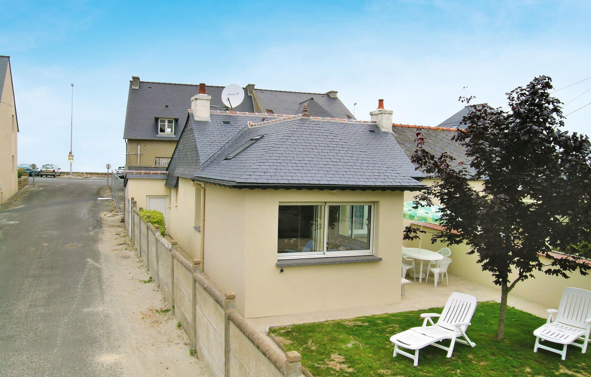 A residential property with a small garden, a white chair, and a table.