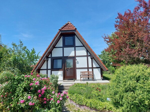 A traditional half-timbered house with a steeply pitched roof, a visible number '139' on the door, and a bench outside.