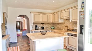 A kitchen with light-colored cabinets, a central island, and a refrigerator. - Amazing home in Callian (Callian)