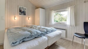 A bedroom with a bed, a chair, a window with curtains, and a wall-mounted light fixture. - Cozy home in Henne with sauna (Henne)