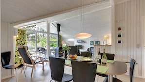 A spacious dining area with a large table, black chairs, and a modern fireplace. - Cozy home in Henne with sauna (Henne)