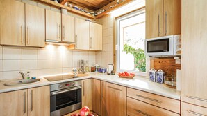 Une cuisine avec des meubles en bois, un four en acier inoxydable, un four à micro-ondes et une fenêtre donnant sur un paysage verdoyant.