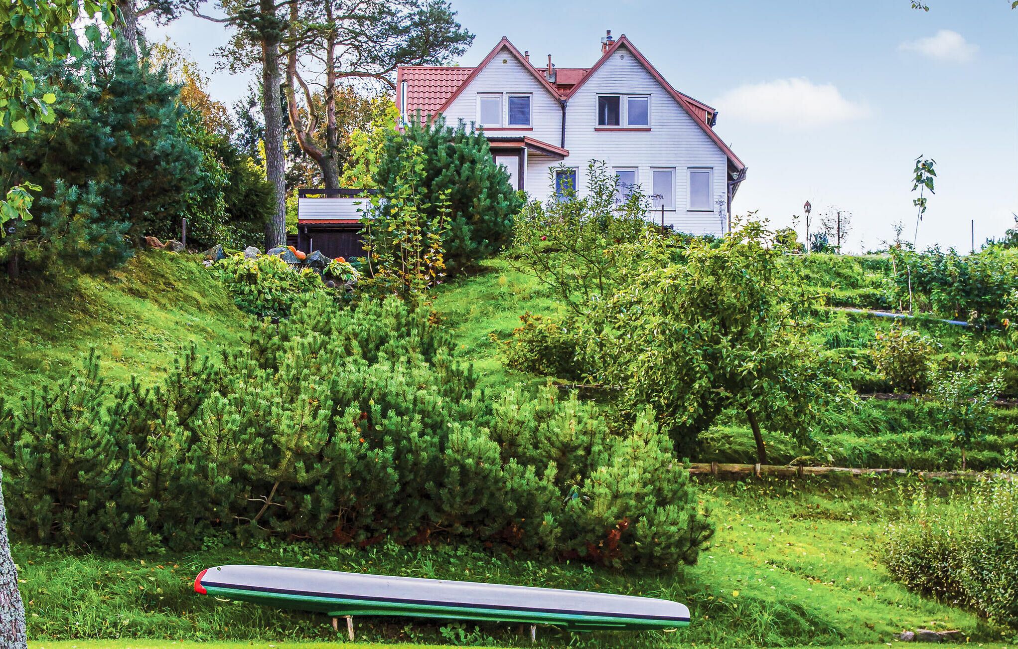 Une maison située sur une colline, avec un bateau vert en premier plan.