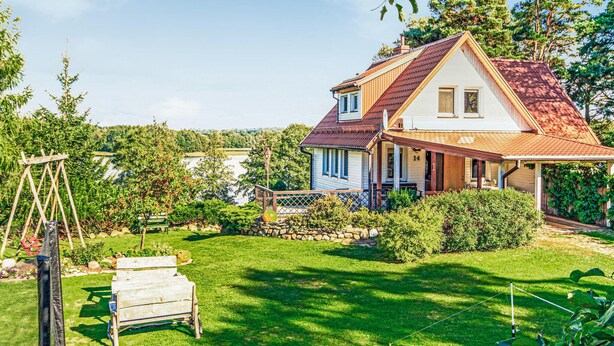 Une maison à deux étages, dotée d’un toit en pente, d’un porche abrité et d’un jardin bien entretenu avec une pelouse et des arbres.