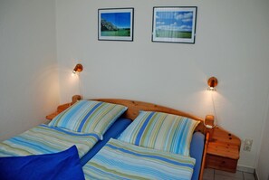Une chambre avec deux lits, une literie à rayures et des lampes fixées au mur.
