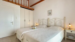 Une chambre avec deux lits, une armoire, une table de chevet avec une lampe et un tableau au mur.
