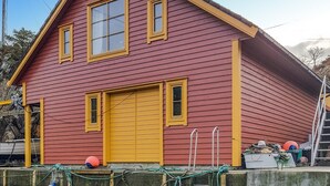 Een huis met twee verdiepingen, een rode gevel en gele details.