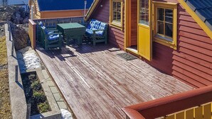Een houten terras met buitenmeubilair, een tafeltje en een bank.