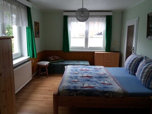 Une chambre à coucher avec un lit, une fenêtre avec des rideaux, un radiateur et une armoire en bois.