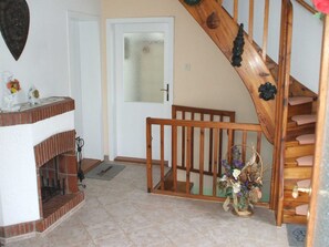 A staircase with wooden railings leading to a second floor, a white door with frosted glass, and a brick fireplace with a decorative mantel.