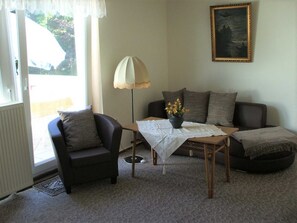 A living room with a sofa, armchair, and a table with a vase of flowers.