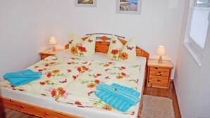 A neatly made bed with floral bedding, two bedside lamps, and a wooden headboard. - Vacation apartment Mönchgut - Holiday apartments in Gager on Rügen (Gager)