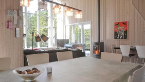 A cozy room with a wooden interior, a foosball table, a fireplace, and a large window offering a view of trees. - Cozy home in Oksbøl with sauna (Oksbøl)