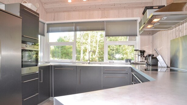 A modern kitchen with a large window, stainless steel appliances, and a clean, minimalist design. - Cozy home in Oksbøl with sauna (Oksbøl)