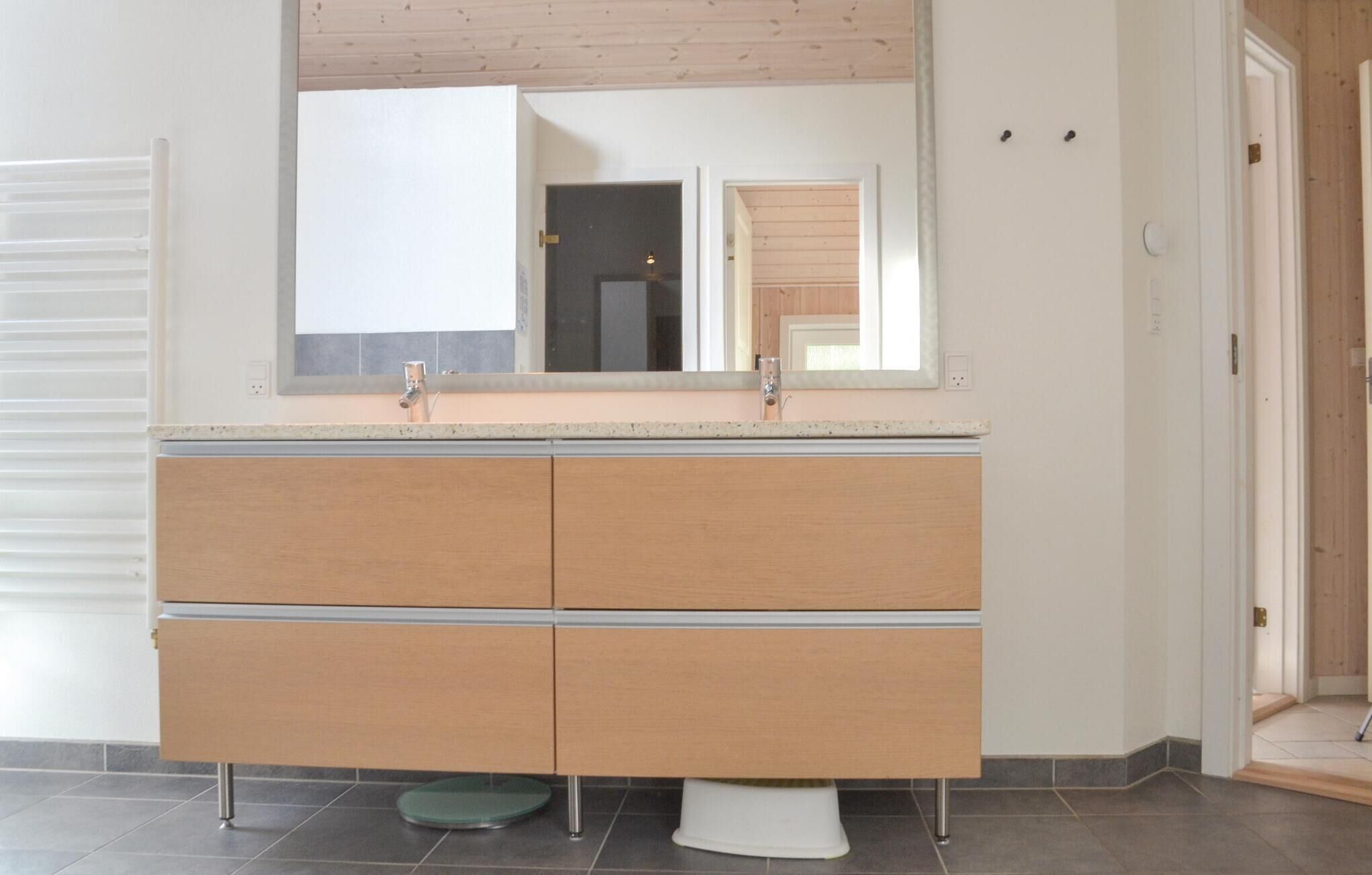 A bathroom with a double sink vanity, a mirror above the sink, and a toilet with a pedestal base.
