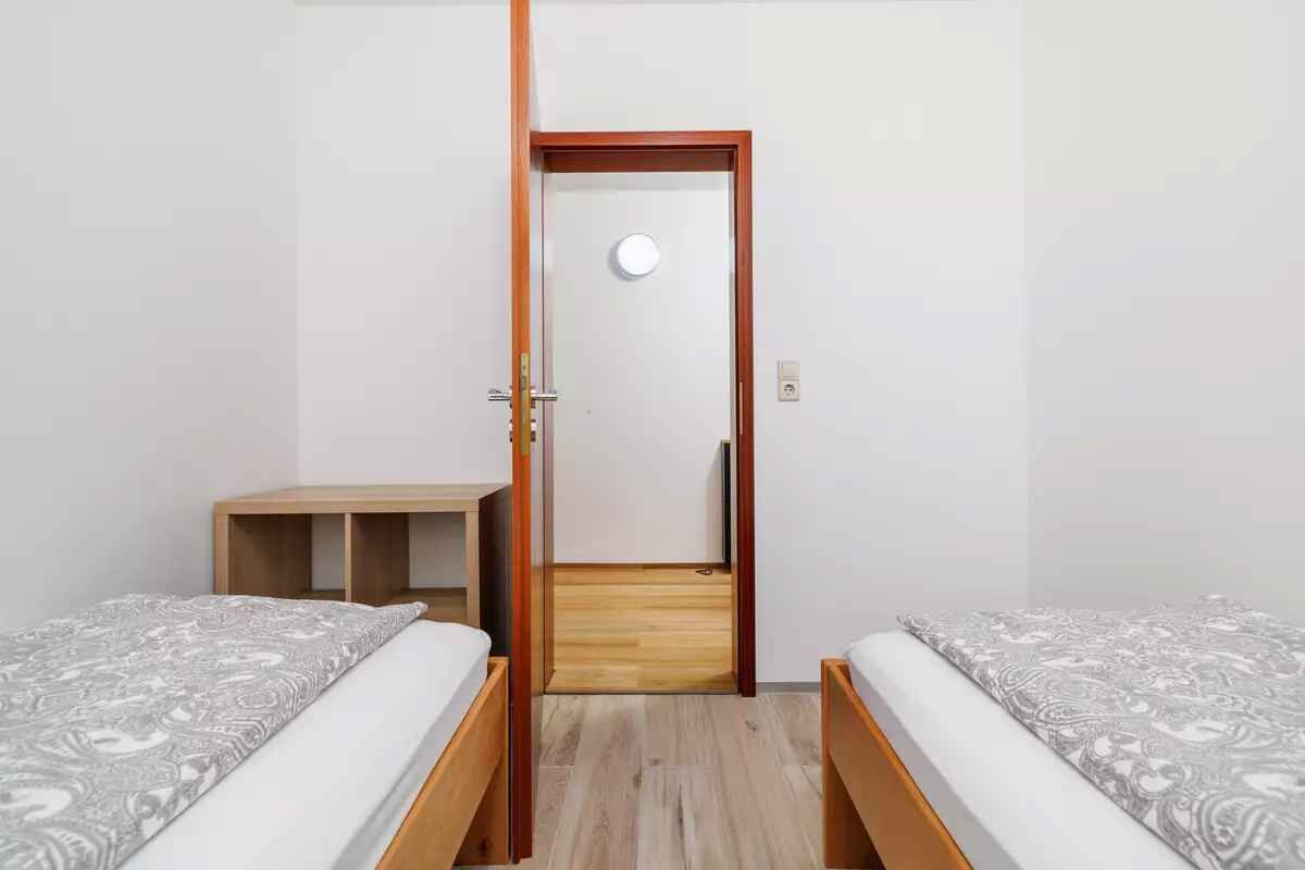 Una habitación con dos camas, una puerta de madera y una mesita.