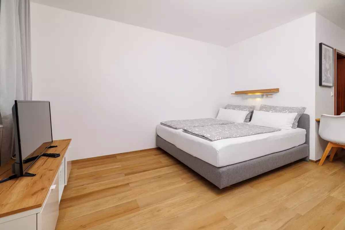 A modern bedroom with a bed, a desk, and a chair.
