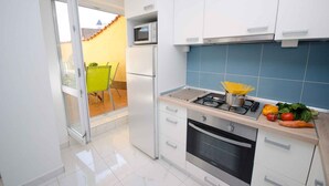 A modern kitchen with white cabinets, a gas stove, and a microwave. - Holiday apartment with terrace (Crikvenica)