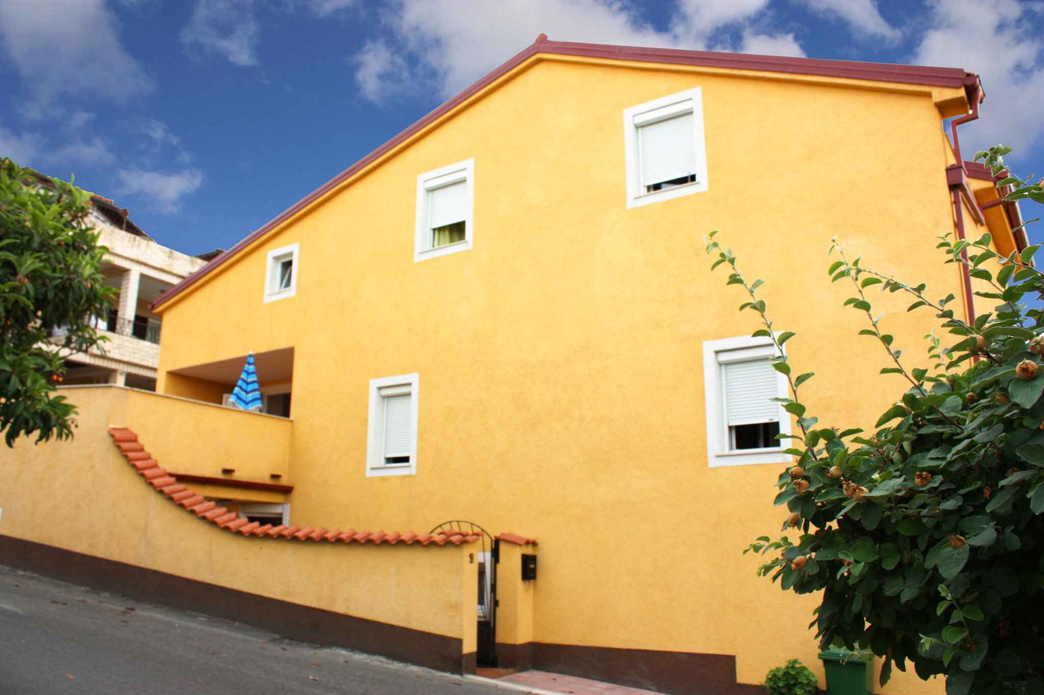 A yellow building with white windows and a red roof.