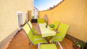 A patio with a table and chairs, a potted plant, and a bottle of wine. - Holiday apartment with terrace (Crikvenica)