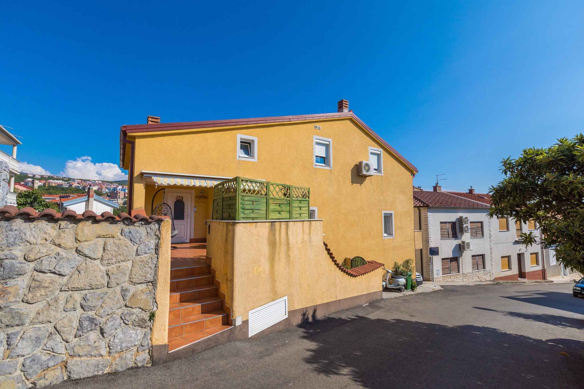 Un edificio giallo con una parete in pietra, una scala e un piccolo giardino.