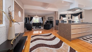 Een moderne woonkamer met een grote zwarte bank, een eethoek en een keuken met granieten aanrechtbladen.