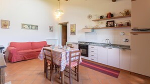 A compact kitchen with a dining area, featuring a red sofa, a table with a checkered tablecloth, and a hanging light fixture. - Pet friendly apartment (S.Vito In Monte TR)