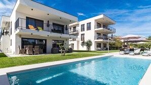 A modern two-story residential building with a swimming pool, outdoor seating, and a well-maintained lawn. - Nice apartment in Medulin (Medulin)