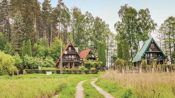 A rural setting with two wooden houses connected by a gravel path.
