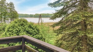 A wooden deck overlooking a lake with dense forest and a clear sky.