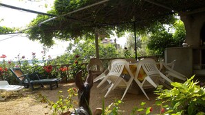 Een terras met een pergola, zitplaatsen buiten en een decoratief paardenbeeld.