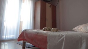 Een slaapkamer met een bed, een kledingkast, een televisie en een airconditioning.