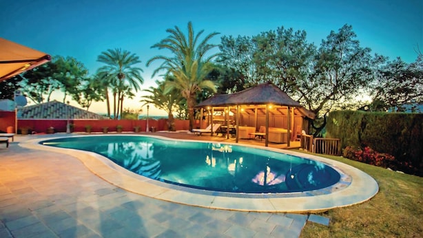 A swimming pool with a sunken hot tub, surrounded by a covered patio area with lounge chairs. - Stunning home in Elviria (Elviria)