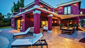 A modern house with a patio area featuring lounge chairs and a dining table. - Stunning home in Elviria (Elviria)